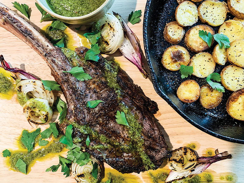 Grilled Tomahawk steak with roasted potatoes, onions and parsley sauce
